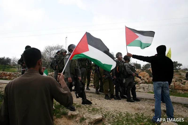 Israeli soldiers take position as Palestinians hold national flag during a protest against the controversial Israeli barrier in the West Bank village of Bilin near Ramallah, Feb. 25, 2011. Photo by Issam Rimawi