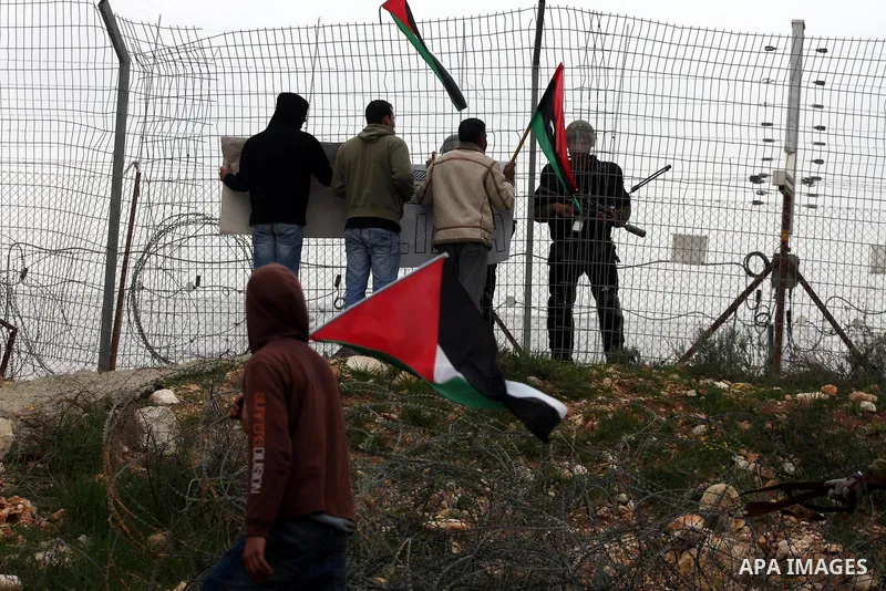 Israeli soldiers take position as Palestinians hold national flag during a protest against the controversial Israeli barrier in the West Bank village of Bilin near Ramallah, Feb. 25, 2011. Photo by Issam Rimawi