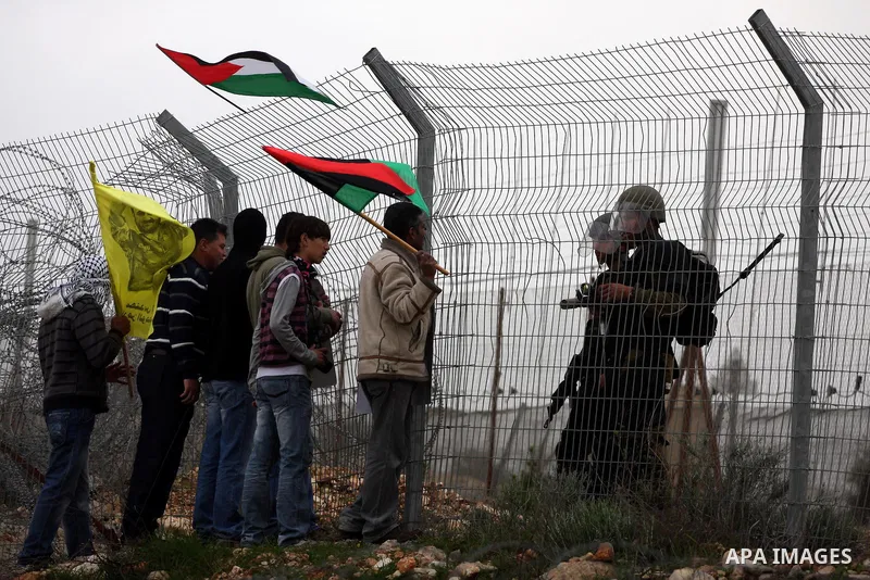 Israeli soldiers take position as Palestinians hold national flag during a protest against the controversial Israeli barrier in the West Bank village of Bilin near Ramallah, Feb. 25, 2011. Photo by Issam Rimawi