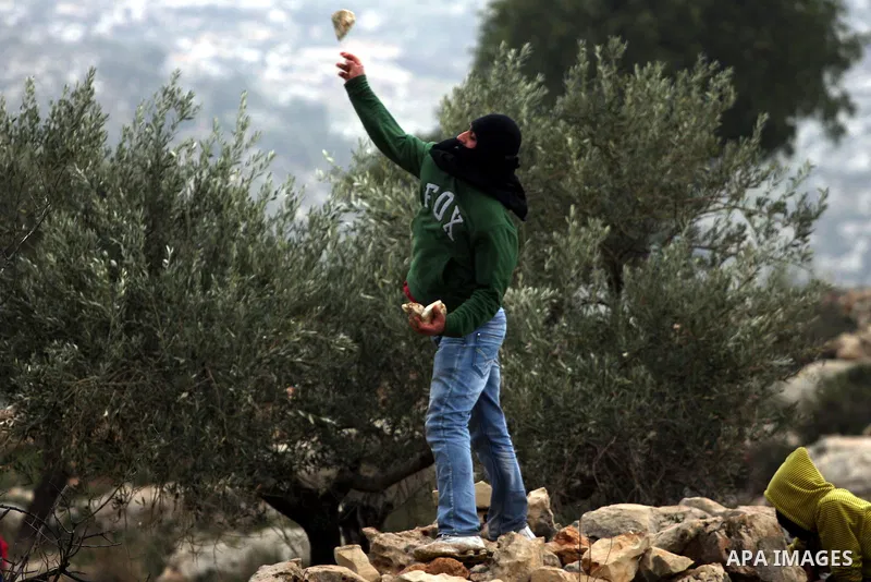 Palestinian youth hurls stones during a protest against the controversial Israeli barrier in the West Bank village of Bilin near Ramallah, Feb. 25, 2011. Photo by Issam Rimawi