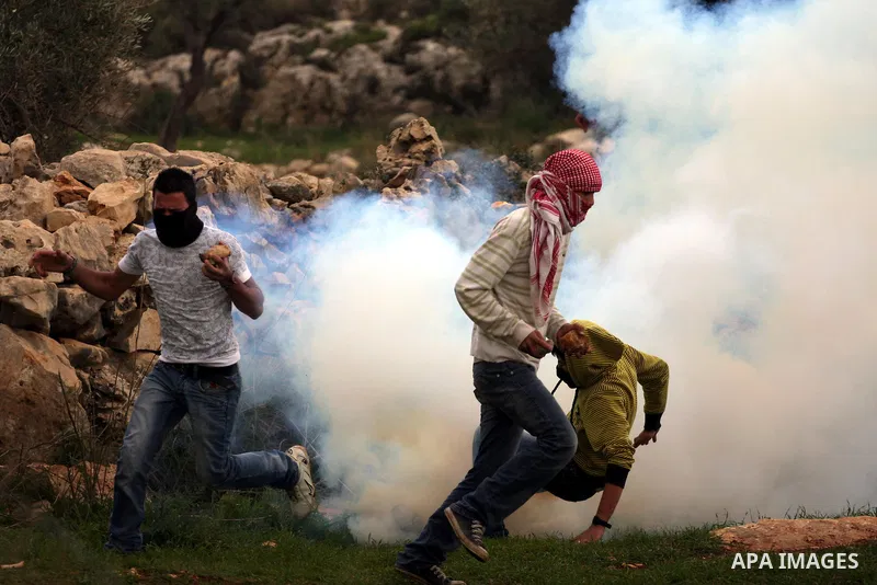 Palestinian youths run for cover from tear gas canisters fired by Israeli soldiers during a protest against the controversial Israeli barrier in the West Bank village of Bilin near Ramallah, Feb. 25, 2011. Photo by Issam...