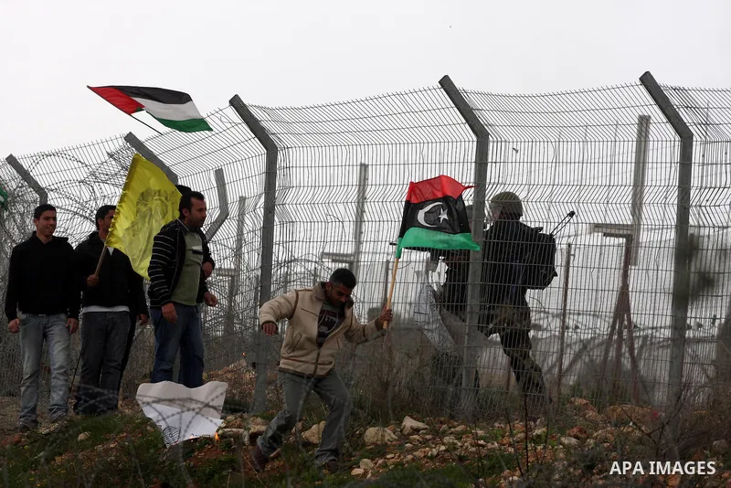 Israeli soldiers take position as Palestinians hold national flag during a protest against the controversial Israeli barrier in the West Bank village of Bilin near Ramallah, Feb. 25, 2011. Photo by Issam Rimawi
