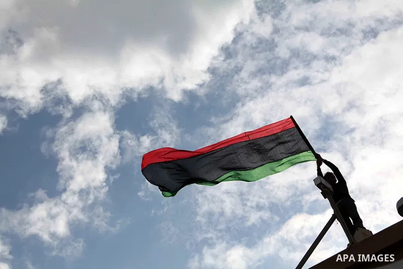 Libyan protester holds the national flag during a rally against Libyan leader Moammar Gadhafi at the Court Square in Derna, Libya, on Feb. 25, 2011. Photo by Karam Nasser