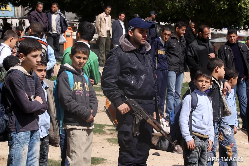 A Member of Palestinian policemen in Gaza Strip, stands guard next to Palestinian boys during a campaign to provide services to the citizen, Gaza City on Feb. 26, 2011. Photo by Mohammed Asad