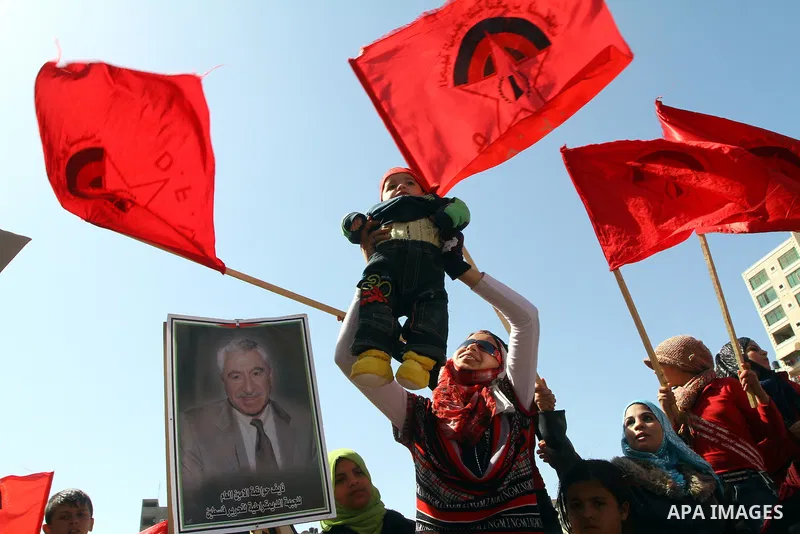 A Palestinian supporter of the Democratic Front for the Liberation of Palestine (DFLP) hold her baby during a rally celebrating 42 years since its founding in Gaza City, Saturday, Feb. 26, 2011. Founded in 1969 the DFLP...