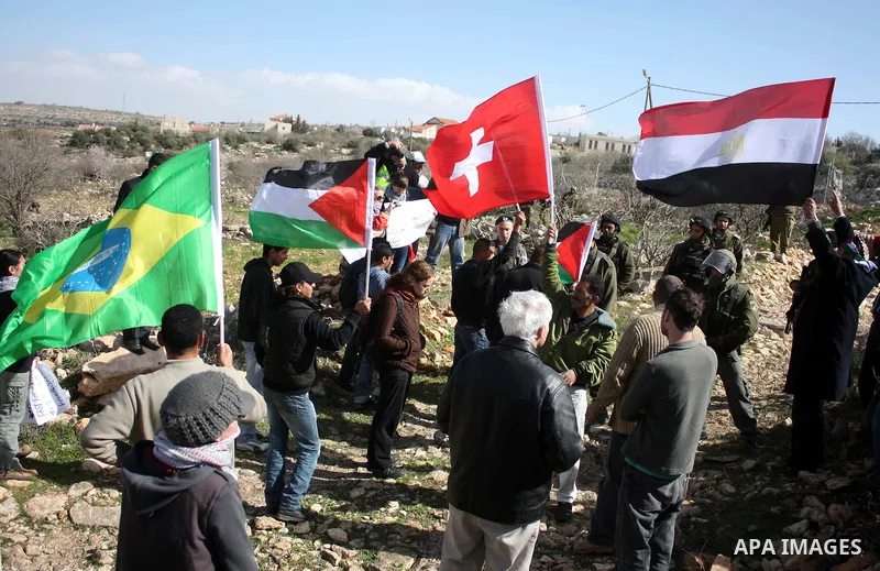 Israeli soldiers stand guard during a demonstration by Palestinian, Israeli and foreign activists against the demolishing of farm land to be used in the construction of Jewish settlements near the existing Israeli settle...