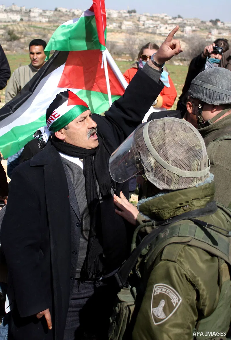 Israeli soldiers stand guard during a demonstration by Palestinian, Israeli and foreign activists against the demolishing of farm land to be used in the construction of Jewish settlements near the existing Israeli settle...