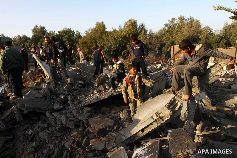 Palestinian onlookers gather at the scene of an Israeli air strike in the al-Burij refugee camp in the central Gaza Strip on February 26, 2011. Israeli warplanes bombed two training camps of the hardline Islamic Jihad gr...