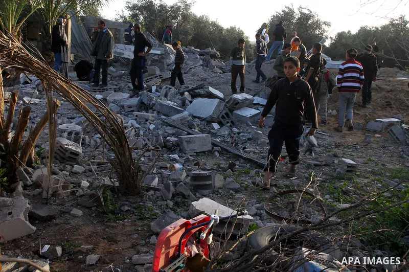 Palestinian onlookers gather at the scene of an Israeli air strike in the al-Burij refugee camp in the central Gaza Strip on February 26, 2011. Israeli warplanes bombed two training camps of the hardline Islamic Jihad gr...