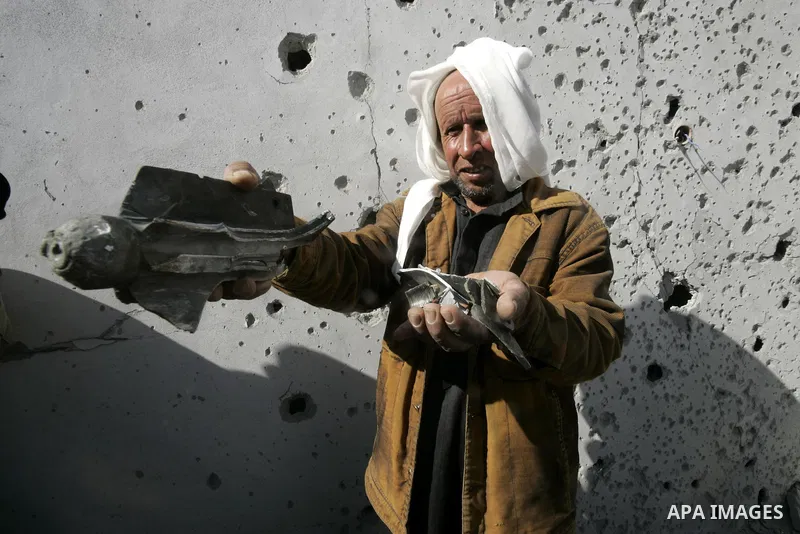 A Palestinian man carries shrapnel that hit house by Israeli artillery, in the southern Gaza strip town of Rafah on February 28, 2011. A Palestinian laborer was injured who was collecting gravel near the airport, while t...