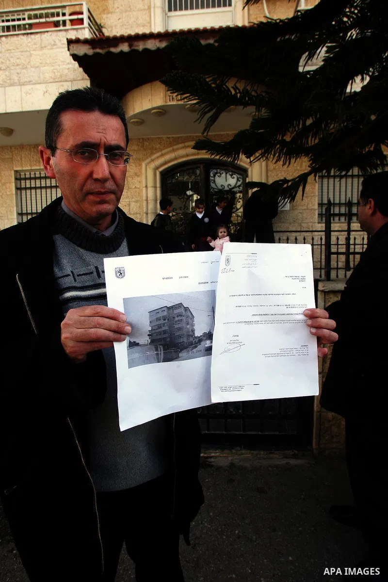 Palestinians stand in front of their house containing six floors after they receive a notice to leave the house as it was built without a permit in the Arab neighborhood of Beit Hanina in occupied east Jerusalem on on Fe...