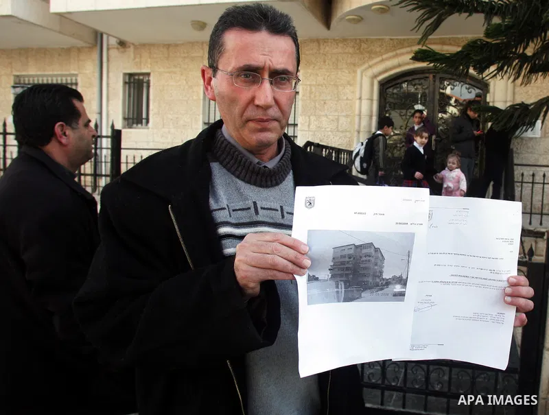 Palestinians stand in front of their house containing six floors after they receive a notice to leave the house as it was built without a permit in the Arab neighborhood of Beit Hanina in occupied east Jerusalem on on Fe...
