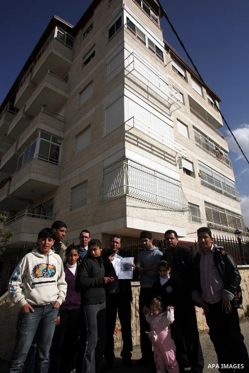 Palestinians stand in front of their house containing six floors after they receive a notice to leave the house as it was built without a permit in the Arab neighborhood of Beit Hanina in occupied east Jerusalem on on Fe...