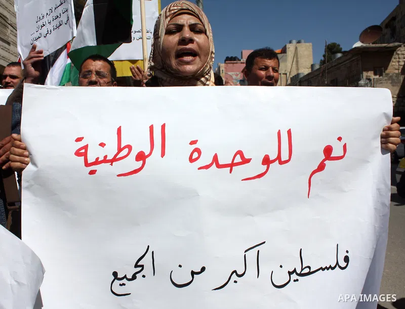 Palestinian protestors hold national flags and banners during a rally against the U.S. veto and calling for the national reconciliation, in the West Bank city of Hebron, on March 03, 2011. Photo by Najeh Hashlamoun