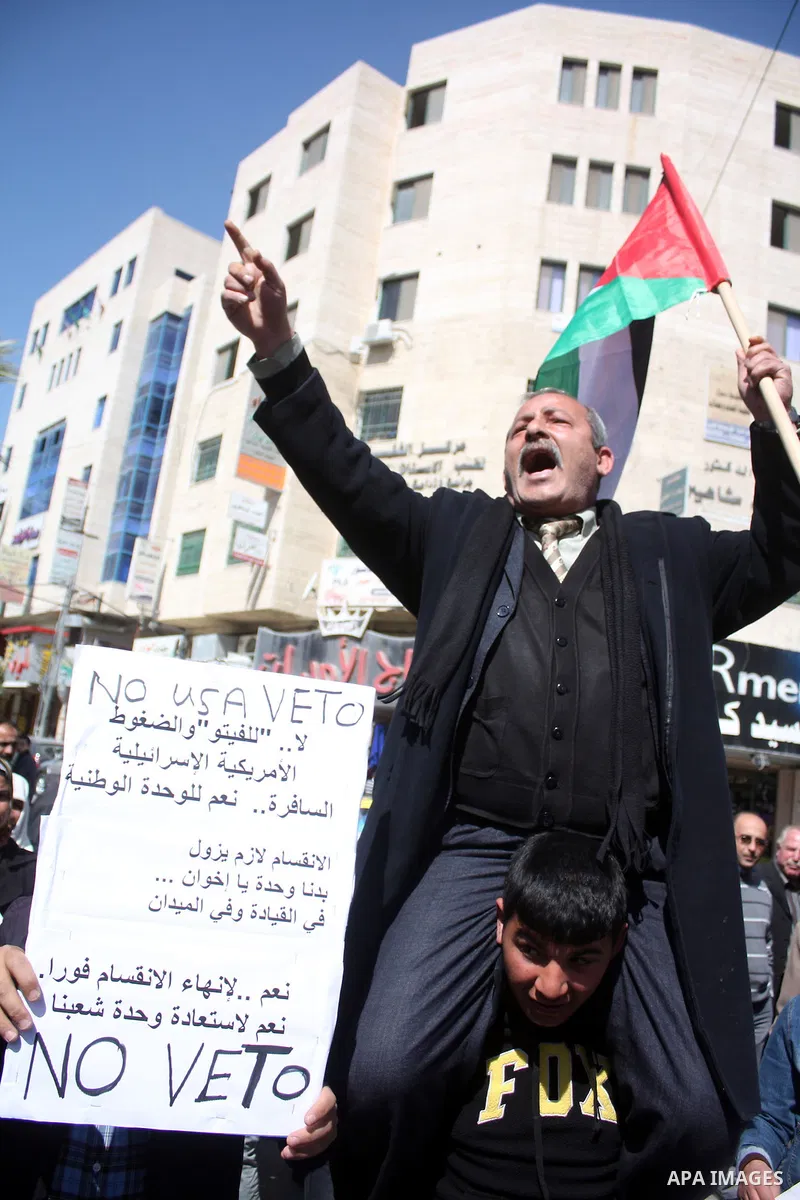 Palestinian protestors hold national flags and banners during a rally against the U.S. veto and calling for the national reconciliation, in the West Bank city of Hebron, on March 03, 2011. Photo by Najeh Hashlamoun