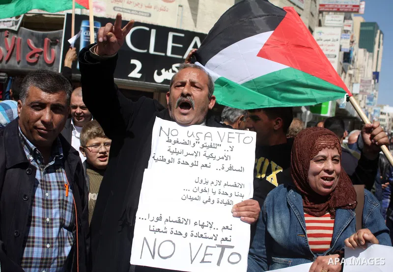 Palestinian protestors hold national flags and banners during a rally against the U.S. veto and calling for the national reconciliation, in the West Bank city of Hebron, on March 03, 2011. Photo by Najeh Hashlamoun