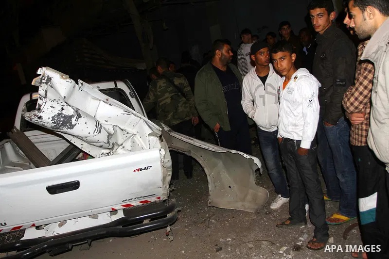 Palestinians inspect a car damaged by an Israeli airstrike, in the central Gaza Strip, March 4, 2011. Palestinian official said that Israeli aircraft struck a car on Friday with no injures.. Photo by Ashraf Amra
