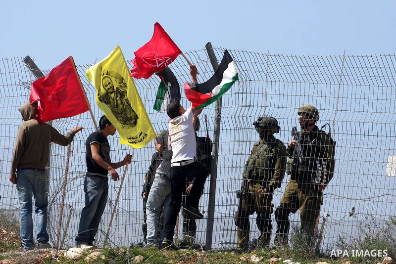 Palestinian youths hold national flags during a protest against Israel's controversial separation barrier in the village of Bilin, near the West Bank city of Ramallah, in the Israeli occupied West Bank, on March 4, 2011....