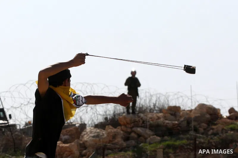 A Palestinian youth hurls a stone at Israeli soldiers during a protest against Israel's controversial separation barrier in the village of Bilin, near the West Bank city of Ramallah, in the Israeli occupied West Bank, on...