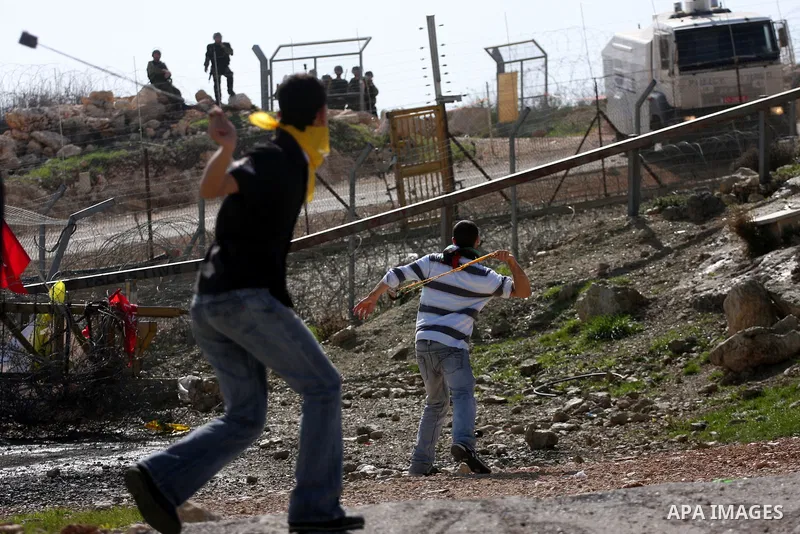 A Palestinian youth hurls a stone at Israeli soldiers during a protest against Israel's controversial separation barrier in the village of Bilin, near the West Bank city of Ramallah, in the Israeli occupied West Bank, on...