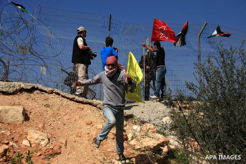 Palestinian demonstrators holds Palestinian flags during a protestagainst the construction of Israel's separation barrier in the West Bank village of Bilin near Ramallah, Friday,March 4, 2011. Photo by Wagdi Eshtayah
