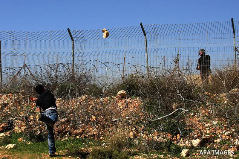 A Palestinian demonstrator hurls stones at Israeli troops during a protest against the construction of Israel's separation barrier in the West Bank village of Bilin near Ramallah, Friday,March 4, 2011. Photo by Wagdi Esh...