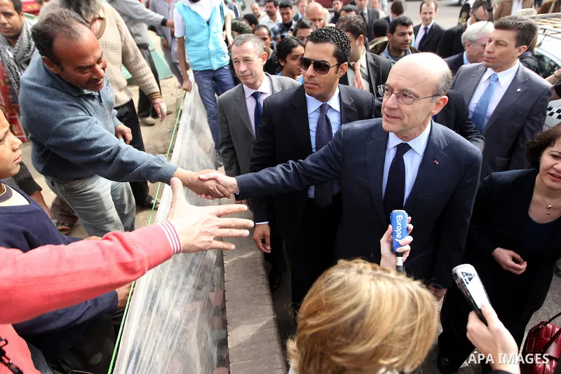 French newly appointed Foreign Minister Alain Juppe salutes people as he visits Cairo's Tahrir square on March 6, 2011 as part of a visit during which he affirmed his country's commitment to Egypt. Juppe, speaking to the...