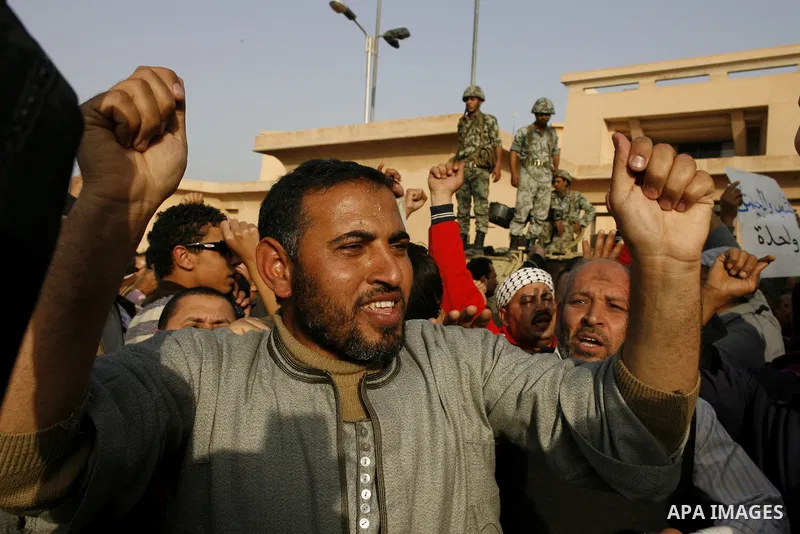 Egyptian protesters chant slogans during a demonstration in front of an Egyptian state security building in the outskirts of Cairo on Mach 5, 2011 while state security employees briefly fired gunshots as hundreds of prot...