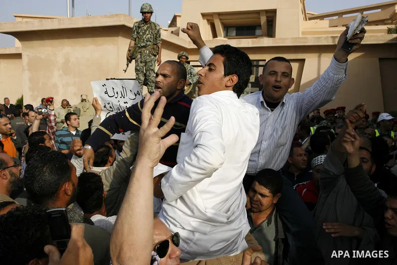 Egyptian protesters chant slogans during a demonstration in front of an Egyptian state security building in the outskirts of Cairo on Mach 5, 2011 while state security employees briefly fired gunshots as hundreds of prot...