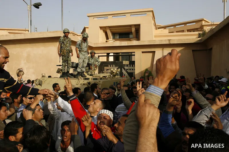Egyptian protesters chant slogans during a demonstration in front of an Egyptian state security building in the outskirts of Cairo on Mach 5, 2011 while state security employees briefly fired gunshots as hundreds of prot...
