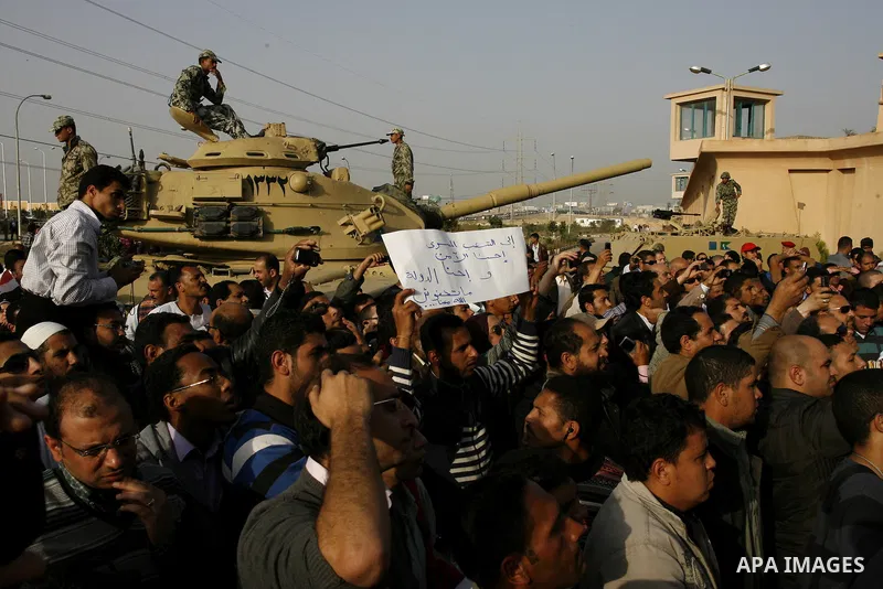 Egyptian protesters chant slogans during a demonstration in front of an Egyptian state security building in the outskirts of Cairo on Mach 5, 2011 while state security employees briefly fired gunshots as hundreds of prot...