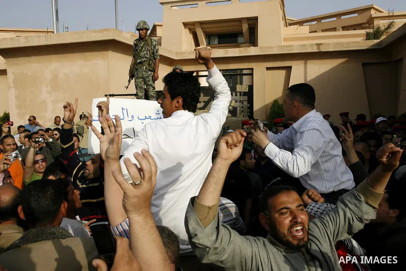 Egyptian protesters chant slogans during a demonstration in front of an Egyptian state security building in the outskirts of Cairo on Mach 5, 2011 while state security employees briefly fired gunshots as hundreds of prot...