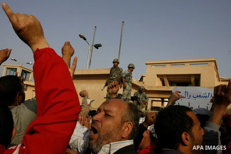 Egyptian protesters chant slogans during a demonstration in front of an Egyptian state security building in the outskirts of Cairo on Mach 5, 2011 while state security employees briefly fired gunshots as hundreds of prot...