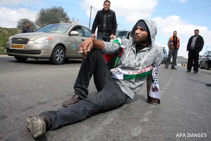 Palestinian men wave their national flag as they sit and block Road 60, which links Jerusalem and Hebron and is used by both Palestinians and Jewish settlers, on March 08,2011 in Beit Omar near the West Bank city of Hebr...