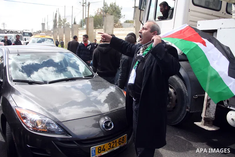 Palestinian men wave their national flag as they sit and block Road 60, which links Jerusalem and Hebron and is used by both Palestinians and Jewish settlers, on March 08,2011 in Beit Omar near the West Bank city of Hebr...