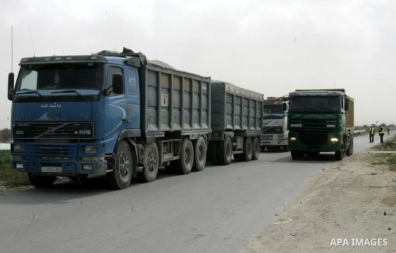 Workers from the United Nations Relief and Works Agency (UNRWA) supervise trucks loaded with gravels at the Sufa border crossing with Israel in the southern Gaza Strip, on March 9, 2011. Israel today allowed gravels to t...