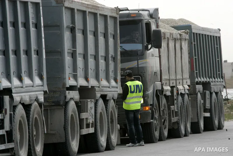 Workers from the United Nations Relief and Works Agency (UNRWA) supervise trucks loaded with gravels at the Sufa border crossing with Israel in the southern Gaza Strip, on March 9, 2011. Israel today allowed gravels to t...