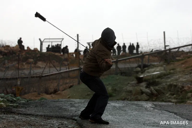 A Palestinian protester hurls stones towards Israeli soldiers during the weekly demonstration against Israel's controversial separation barrier in the village of Bilin, near the West Bank city of Ramallah on March 11, 20...