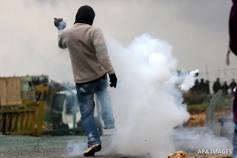 A Palestinian protester returns a tear gas canister towards Israeli soldiers during the weekly demonstration against Israel's controversial separation barrier in the village of Bilin, near the West Bank city of Ramallah...
