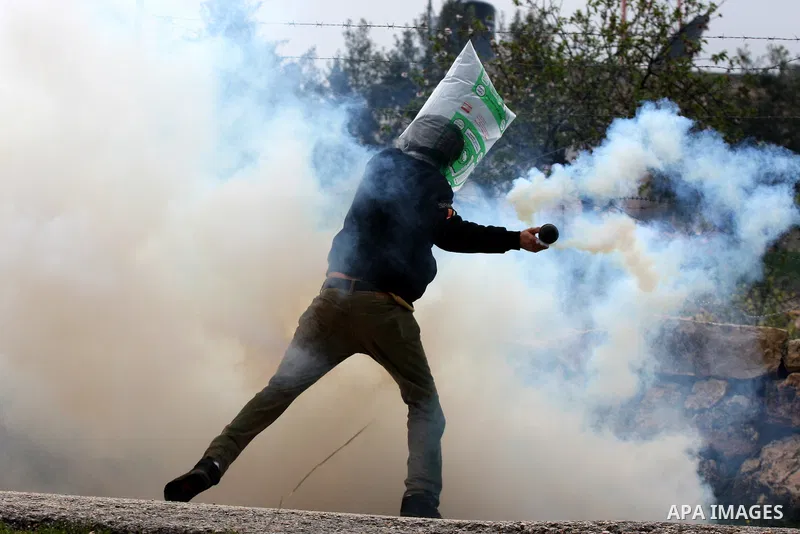 A Palestinian protester returns a tear gas canister towards Israeli soldiers during the weekly demonstration against Israel's controversial separation barrier in the village of Bilin, near the West Bank city of Ramallah...