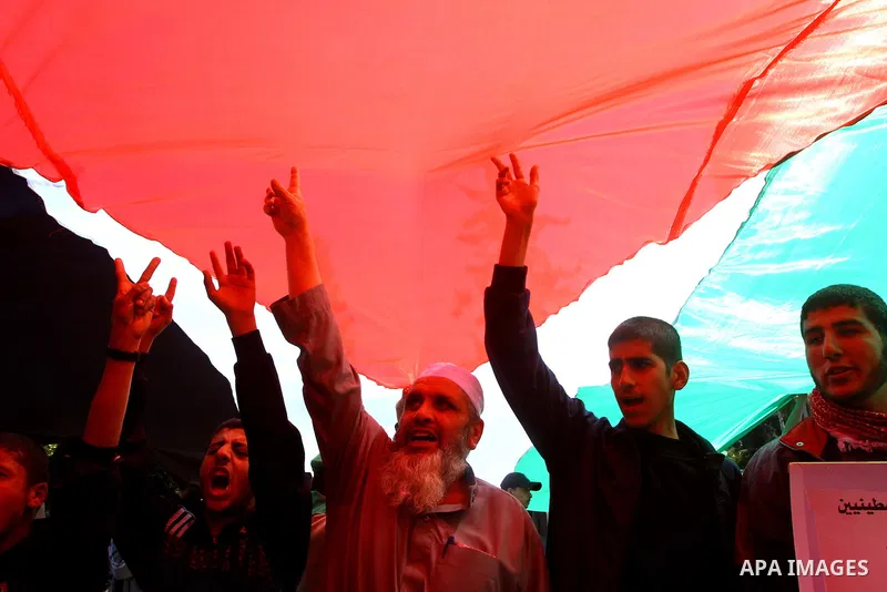 Palestinians hold a giant flag during a protest calling for a national reconciliation between the tow parties Fatah and Hamas in Gaza City on March 12, 2011. Photo by Ashraf Amra