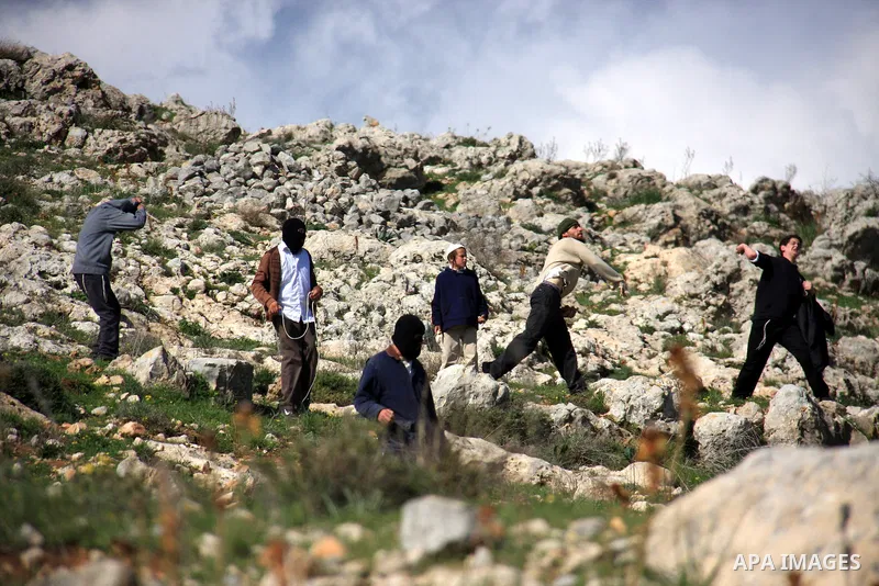 Israeli settlers from the Bracha settlement throw stones at Palestinian youth in the West Bank village of Burin on March 12, 2011 during clashes after an overnight attack in which five members of an Israeli family were k...