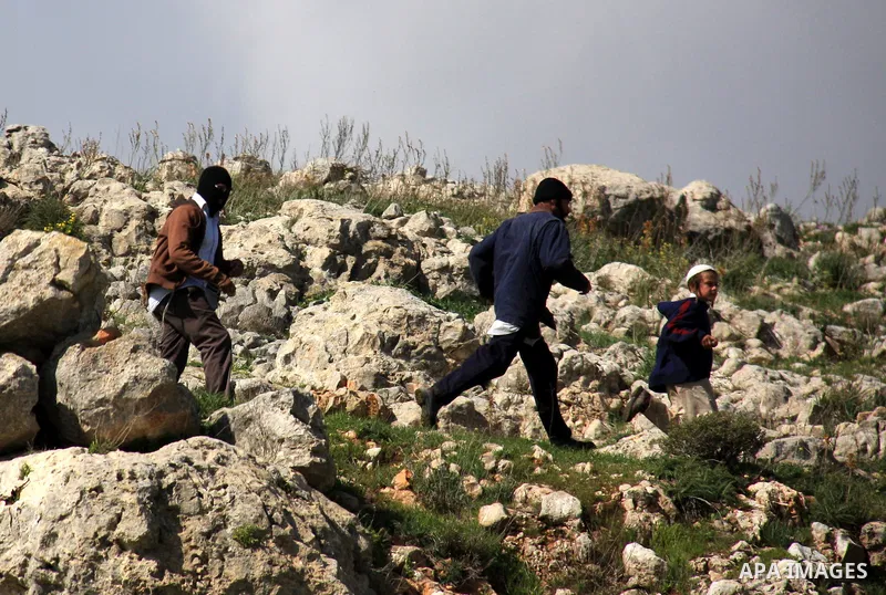 Israeli settlers from the Bracha settlement throw stones at Palestinian youth in the West Bank village of Burin on March 12, 2011 during clashes after an overnight attack in which five members of an Israeli family were k...