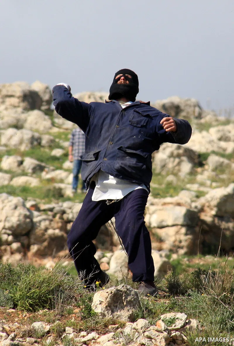 Israeli settlers from the Bracha settlement throw stones at Palestinian youth in the West Bank village of Burin on March 12, 2011 during clashes after an overnight attack in which five members of an Israeli family were k...
