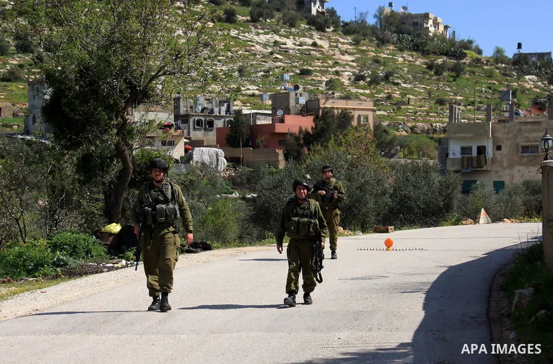 An Israeli soldier stops Palestinians for a security check in the West Bank village of Awarta south of Nablus on 13 March 2011. Israeli troops raided the village, arresting people and searching houses a day after a Pales...