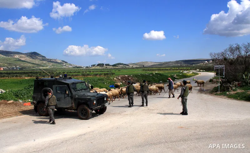 An Israeli soldier stops Palestinians for a security check in the West Bank village of Awarta south of Nablus on 13 March 2011. Israeli troops raided the village, arresting people and searching houses a day after a Pales...