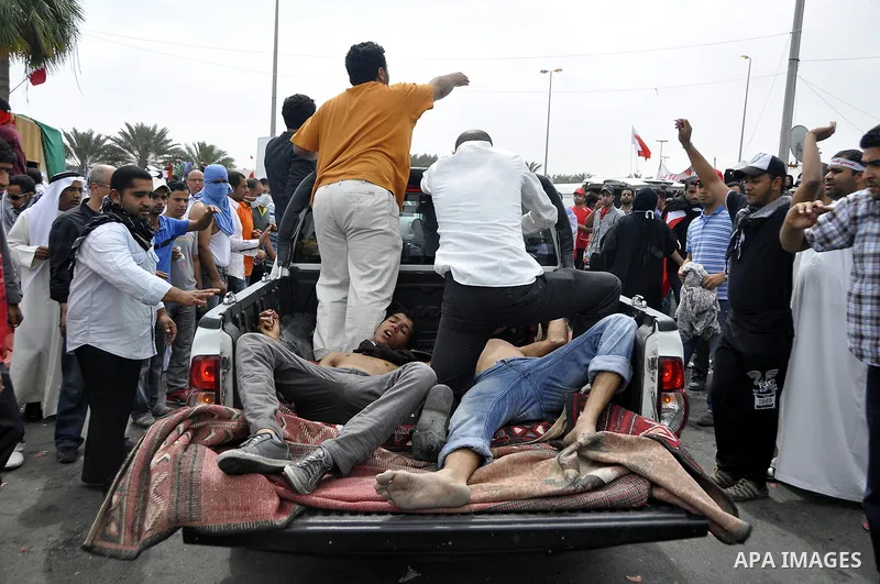 Anti-government protesters carry away fellow demonstrators who was overcome by tear gas fired by riot police Sunday, March 13, 2011, along a main highway in Manama, Bahrain. Photo by Ammar A.rasool