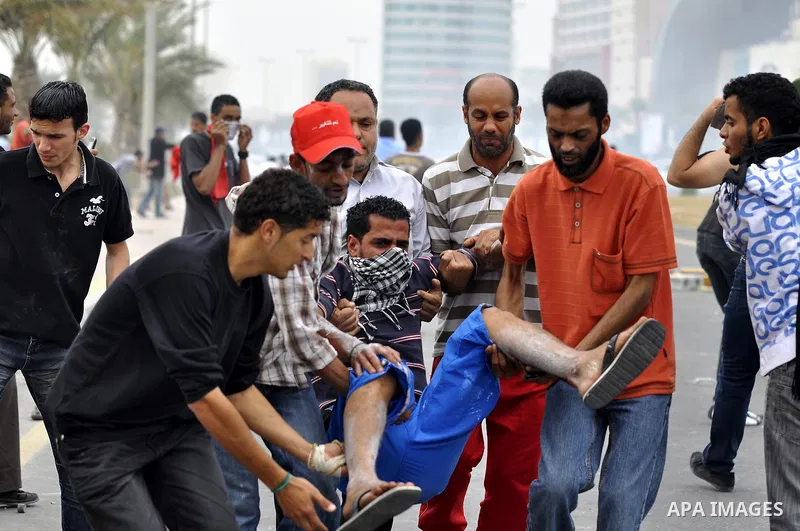 Anti-government protesters carry away a fellow demonstrator who was overcome by tear gas fired by riot police Sunday, March 13, 2011, along a main highway in Manama, Bahrain. Photo by Ammar A.rasool