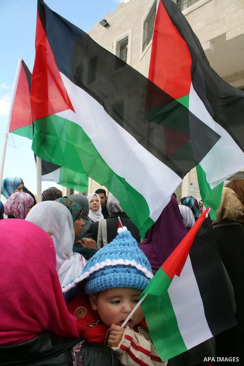 Palestinian women protestors hold national flags and banners calling for the national reconciliation in front of the Governorate of Hebron in the West Bank city of Hebron,on March 13, 2011. Photo by Najeh Hashlamoun