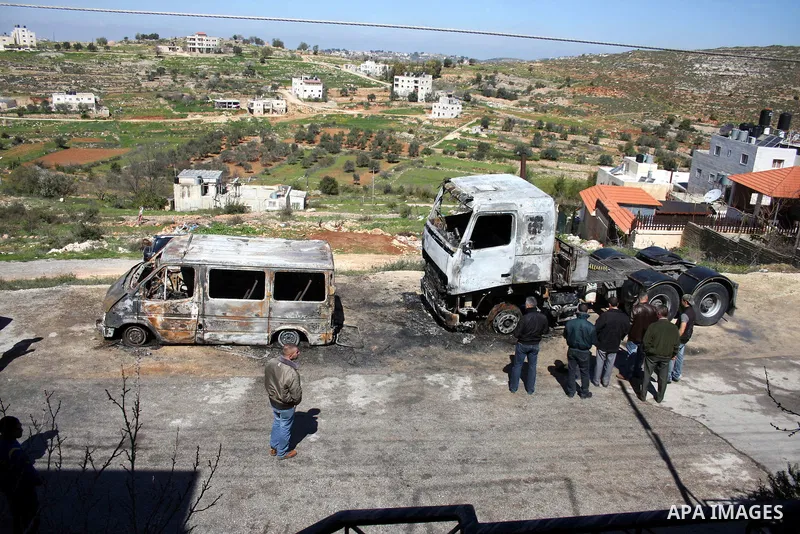 Palestinians stand next to vehicles they said were set on fire by Jewish settlers in retaliation following a deadly attack on a settler family on Friday, in the West Bank in Ramallah, Monday, March 14, 2011. The U.S. Emb...